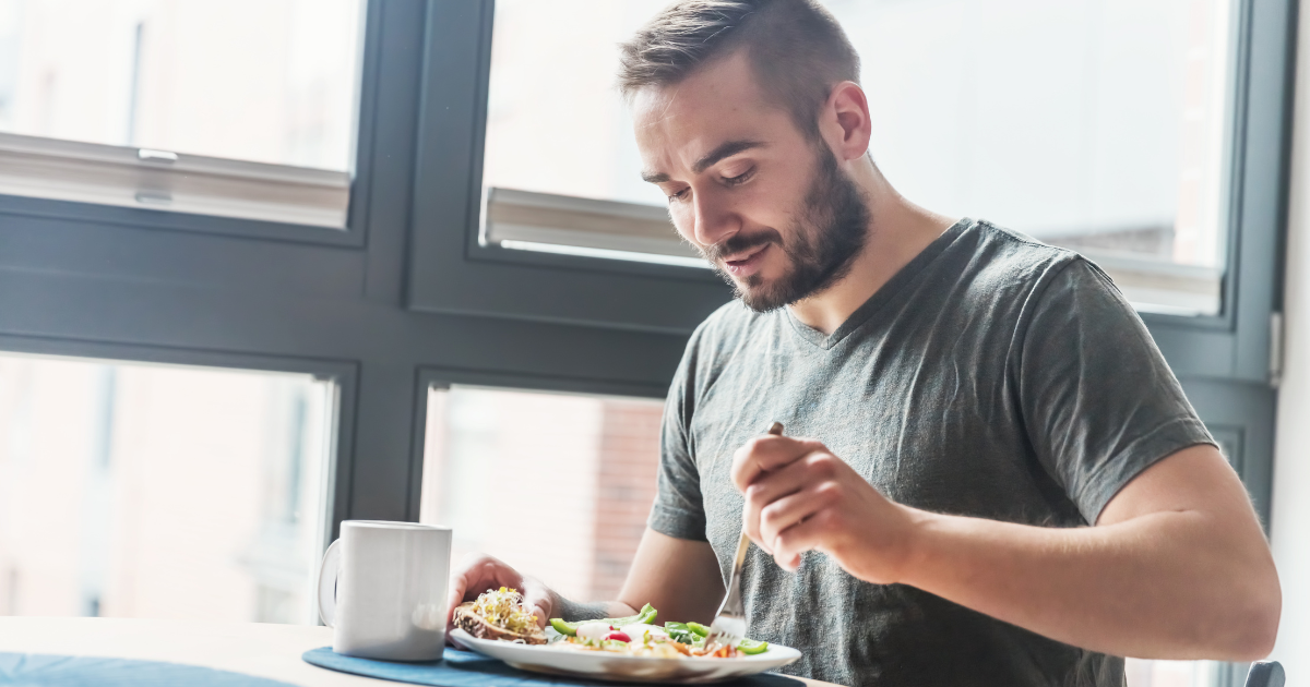 Man with beard eating a healthy meal with a mug